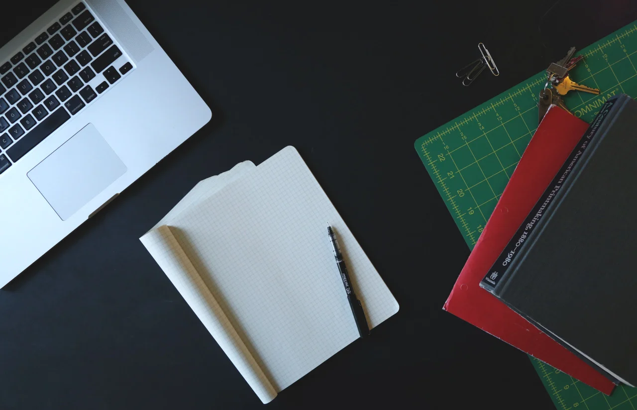 Laptop, notebook and books on a desktop.