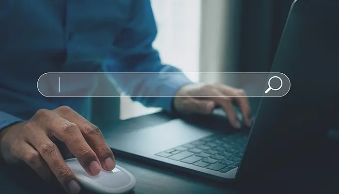 Person using laptop with a search bar graphic overlay.
