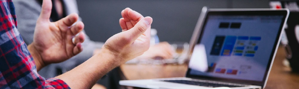 Hands gesturing in front of laptop