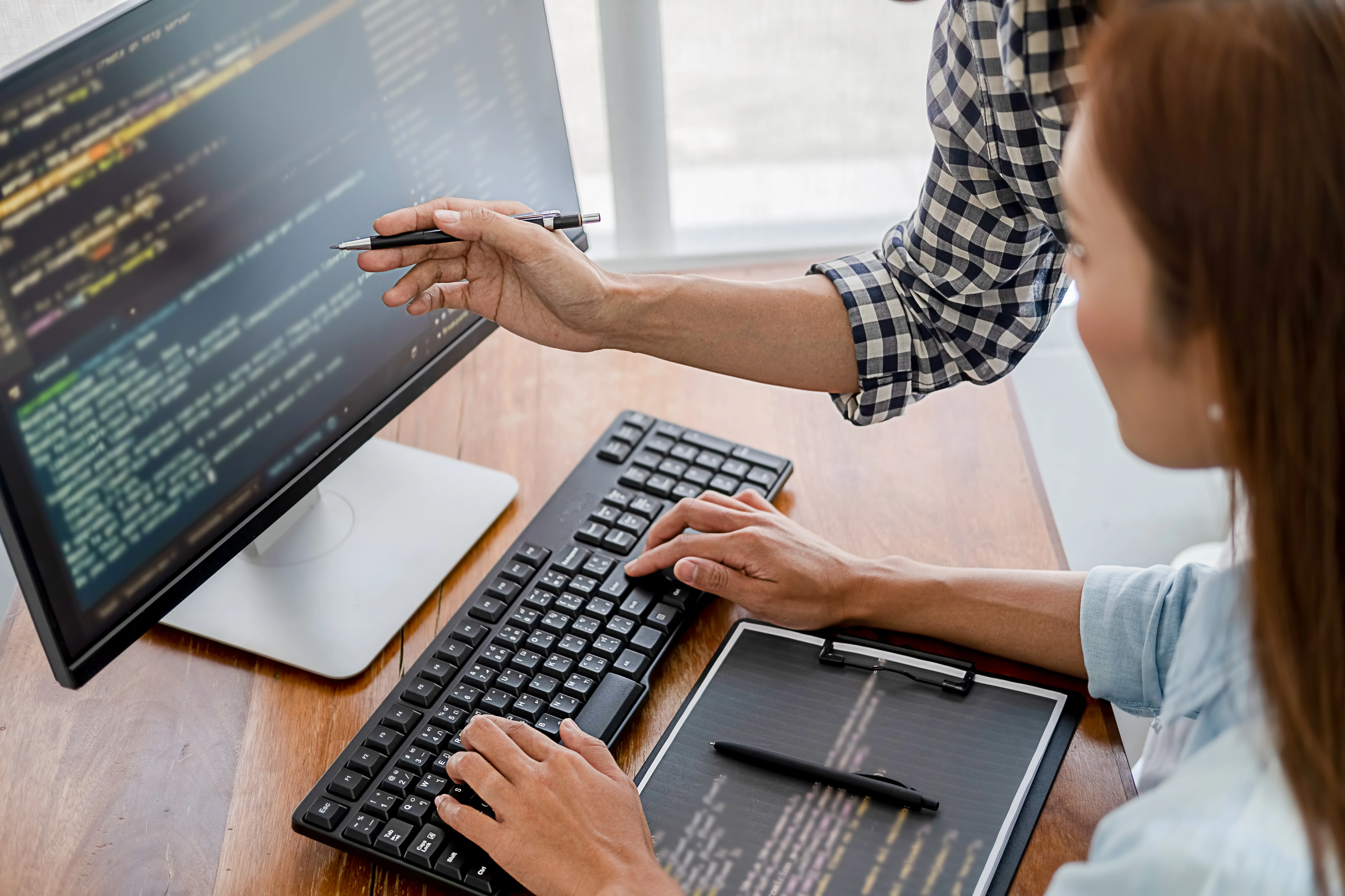 person pointing to computer code on a desktop