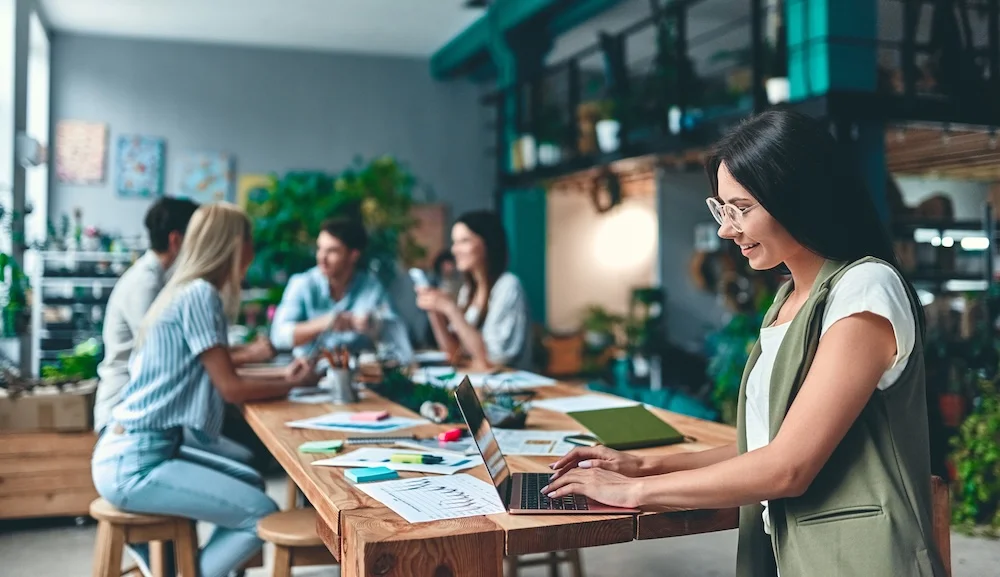 Young open office with girl on laptop in foreground