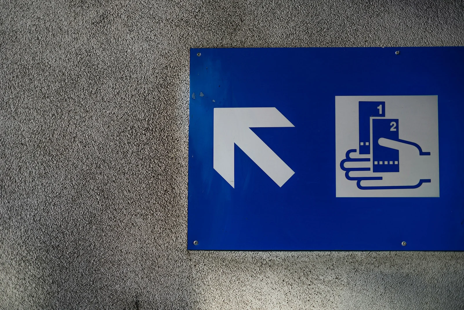 Way finding sign showing arrow and 2 tickets being held in hand.